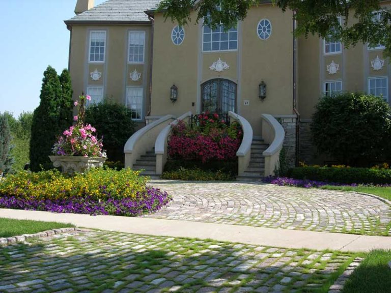 front side of a beige house with a circle drive in the front yard paved with granite setts from Historical Bricks